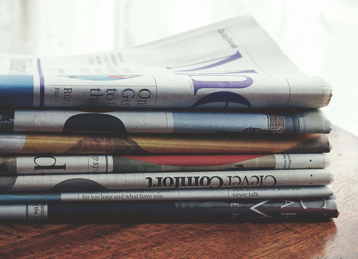 A stack of folded newspapers on a wooden table A stack of folded newspapers on a wooden table
