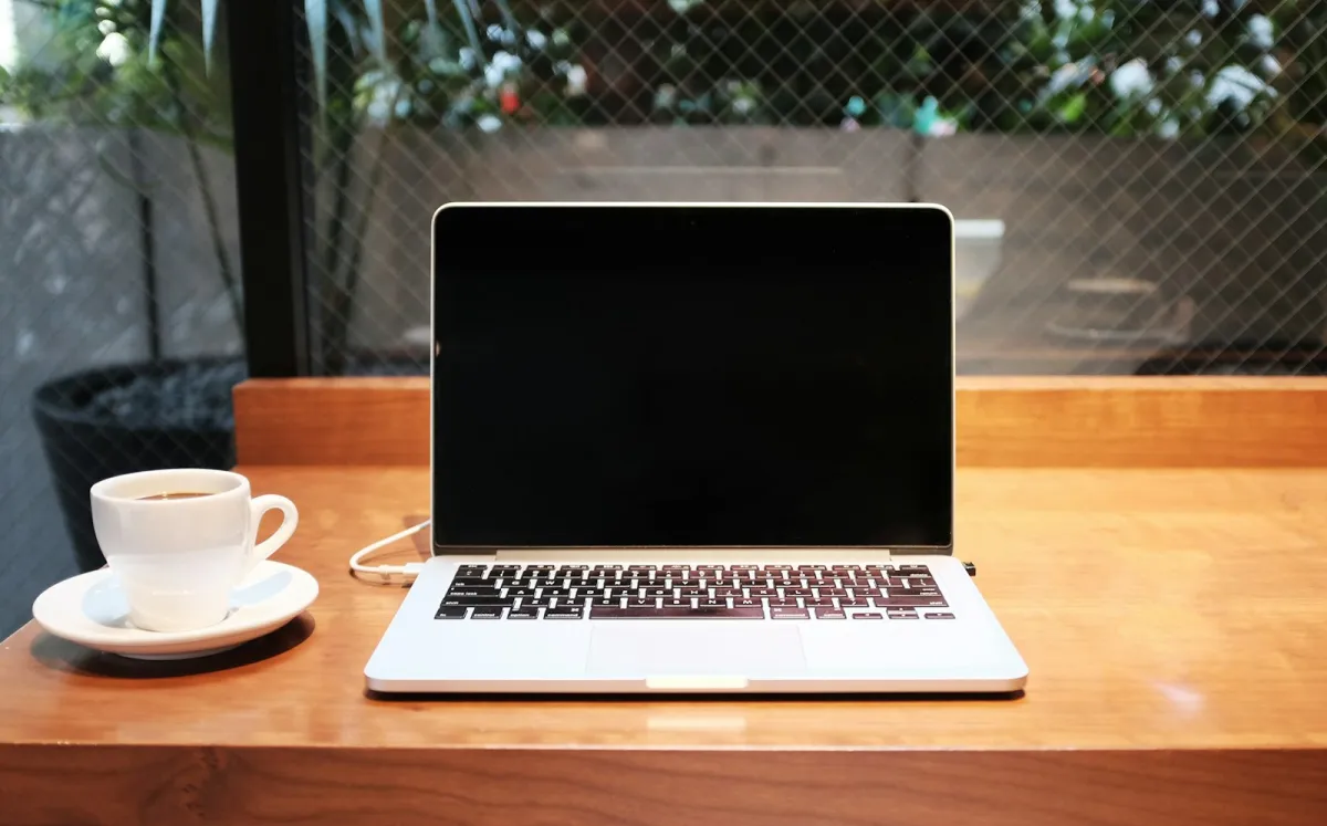 Laptop computer on a desk beside a coffee mug