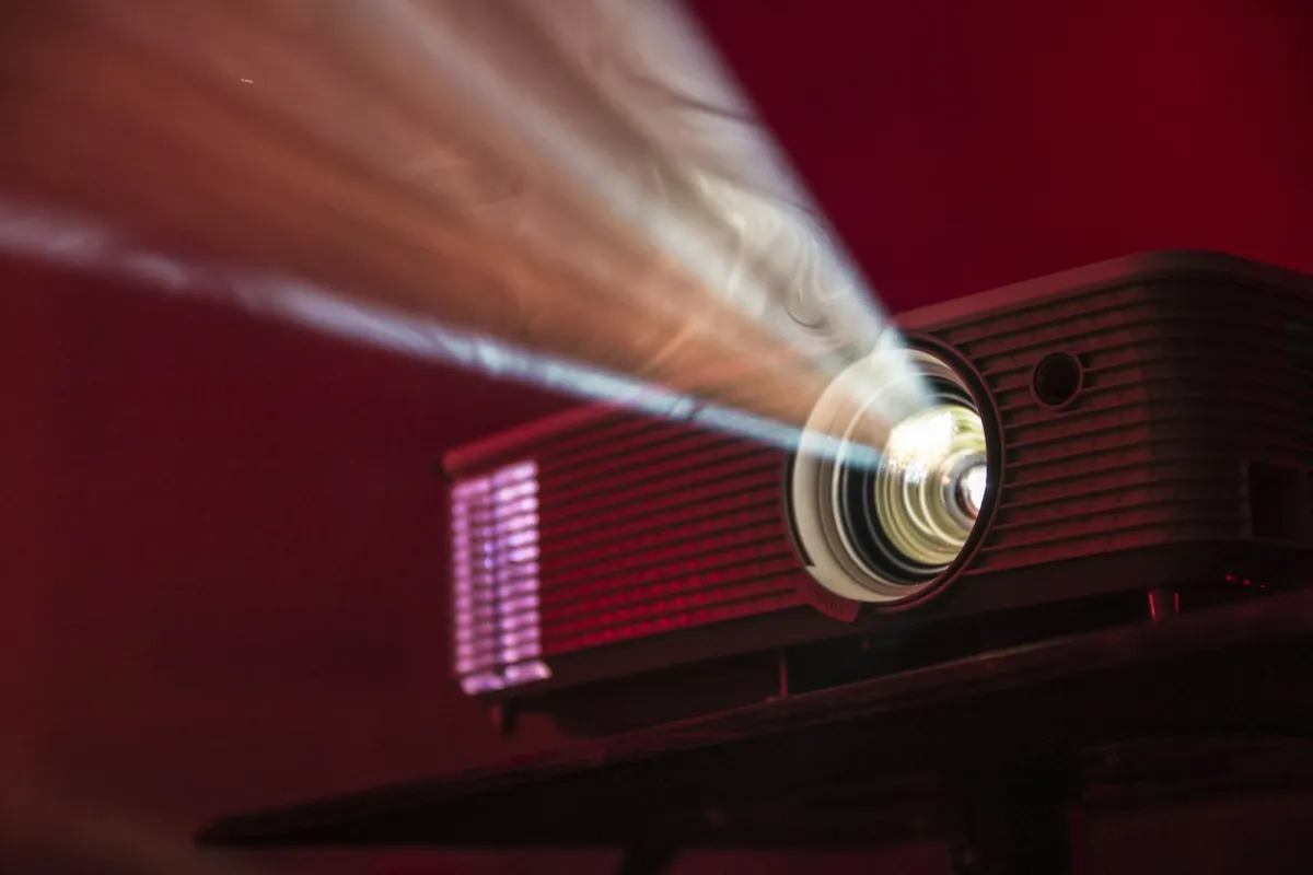 A home projector beaming light across a dark red room