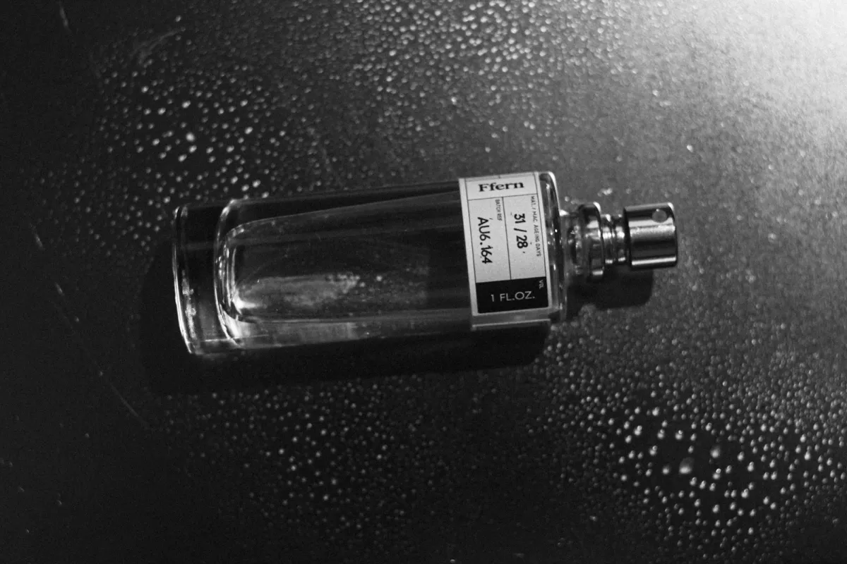 A clear glass perfume bottle with a silver cap A clear glass perfume bottle with a silver cap