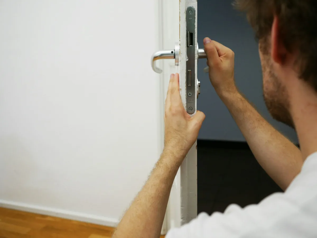 A person fitting a lock and handle to a door A person fitting a lock and handle to a door