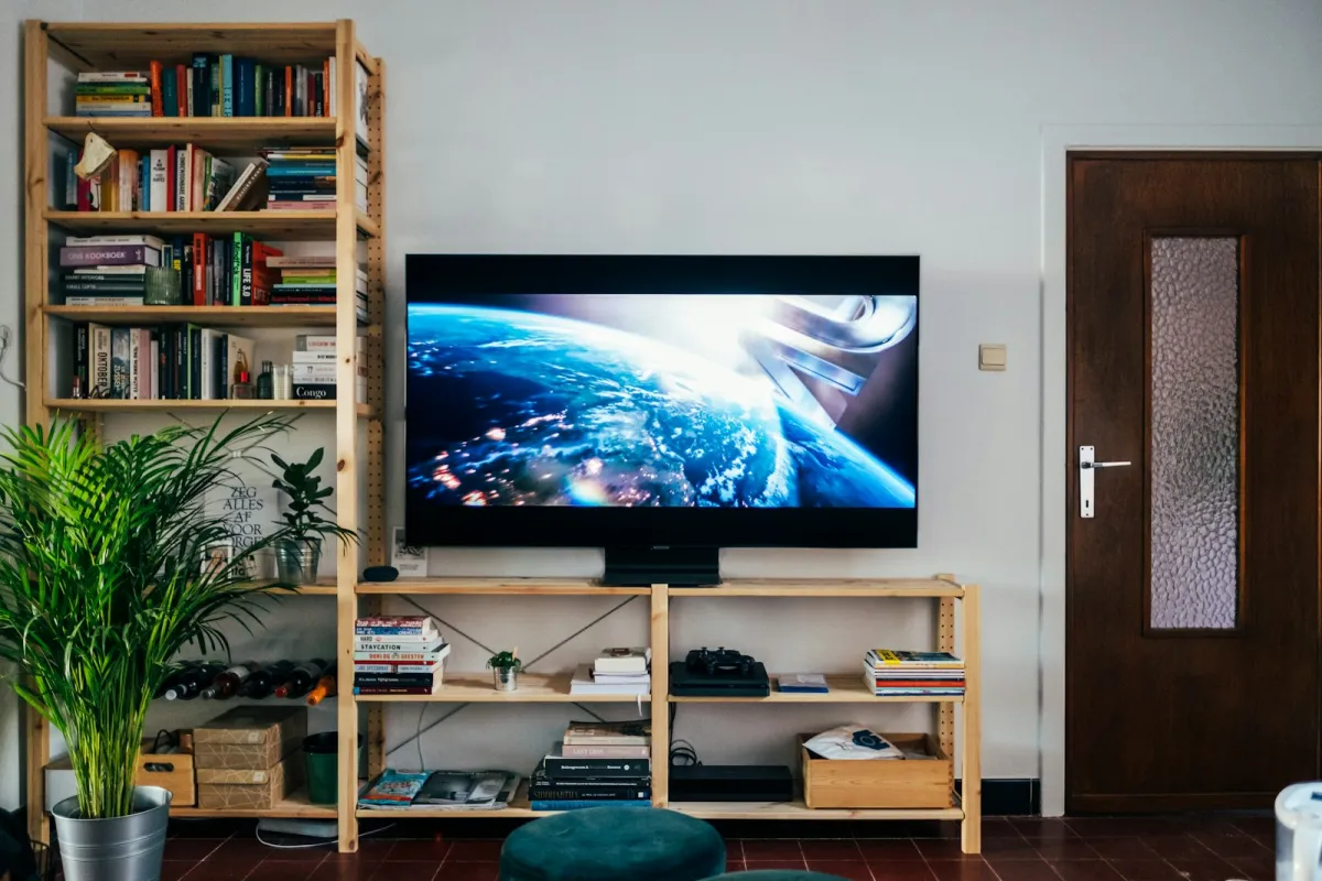 A flat-screen TV on a wooden shelf unit in a living room A flat-screen TV on a wooden shelf unit in a living room