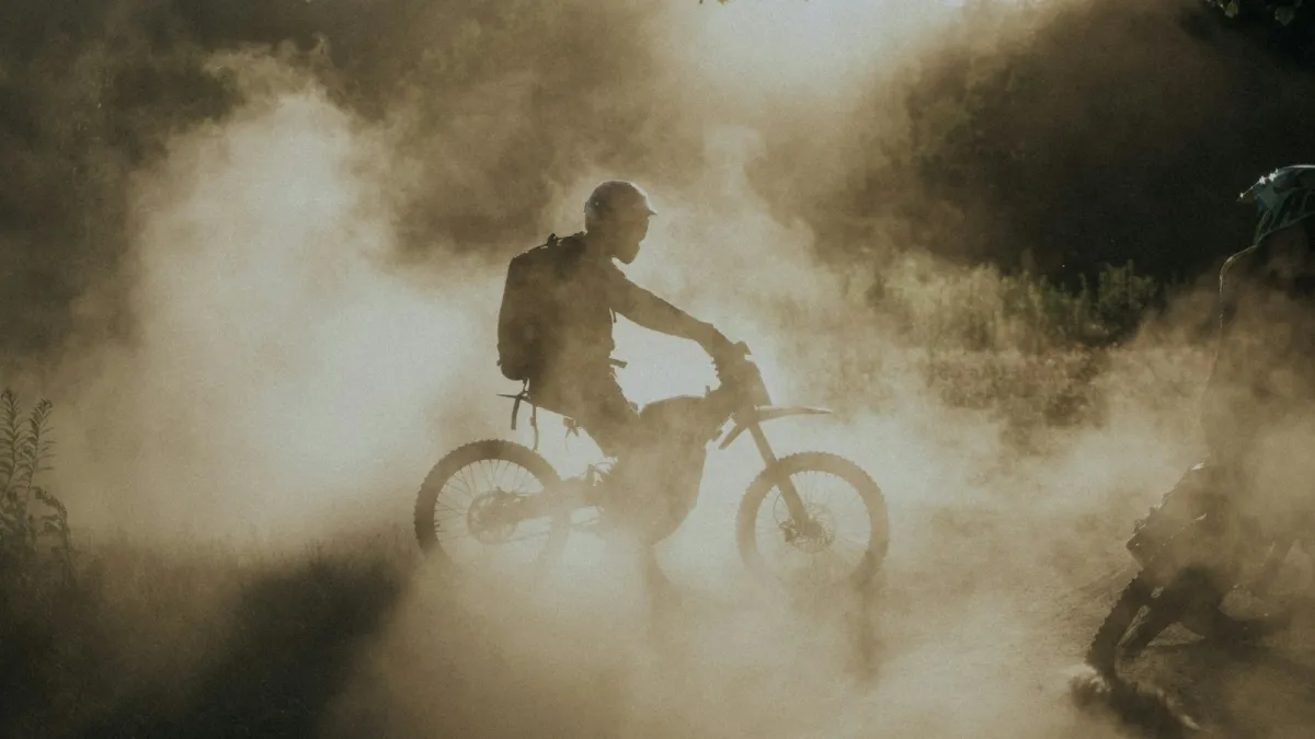 A rider on an electric dirt bike in a cloud of dust