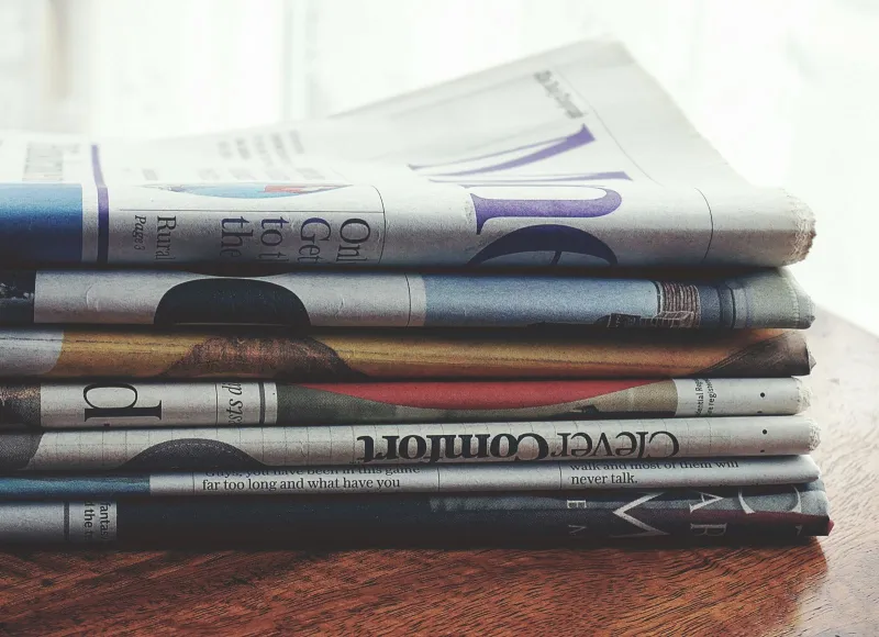 A stack of folded newspapers on a wooden table