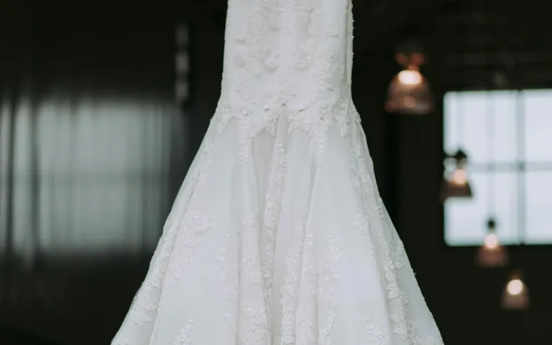Lace-trimmed white gown hanging in a dark room