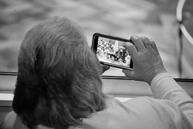 An older person, seen from behind, holding a smartphone in both hands