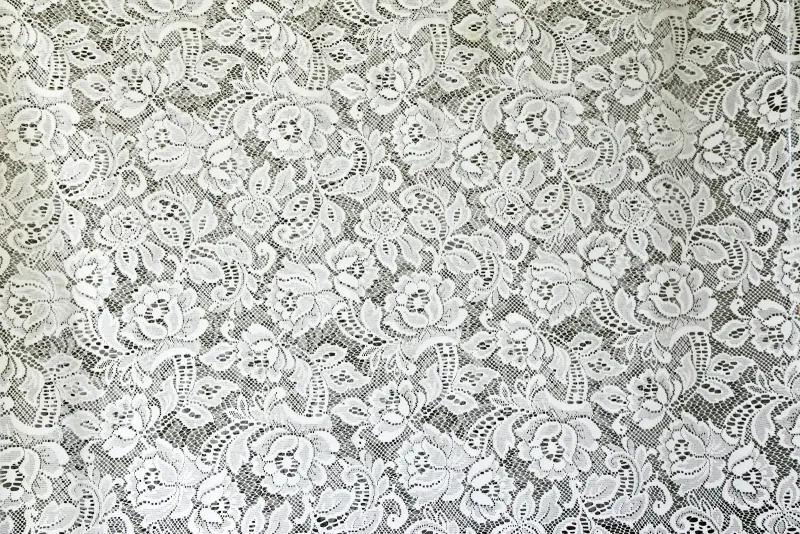 Close-up of white floral lace over a dark background