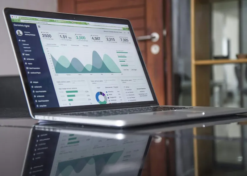 Laptop on a glass table showing charts and statistics