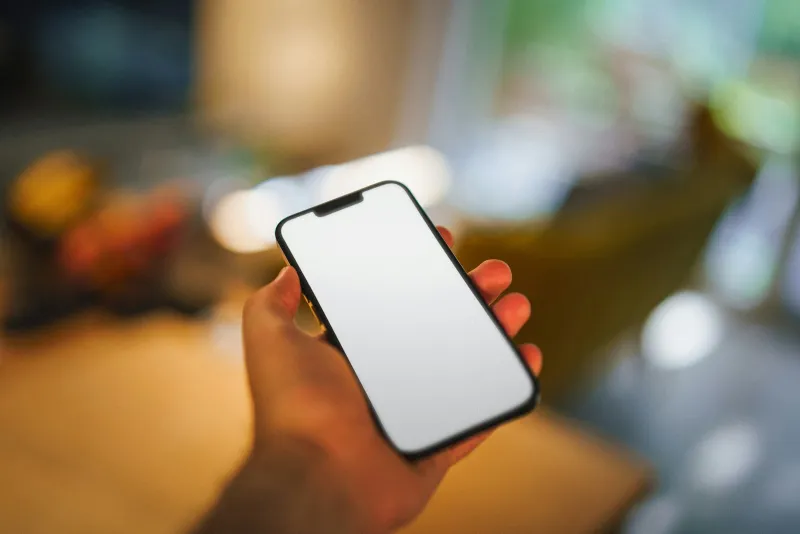 A hand holding a smartphone with a blank screen