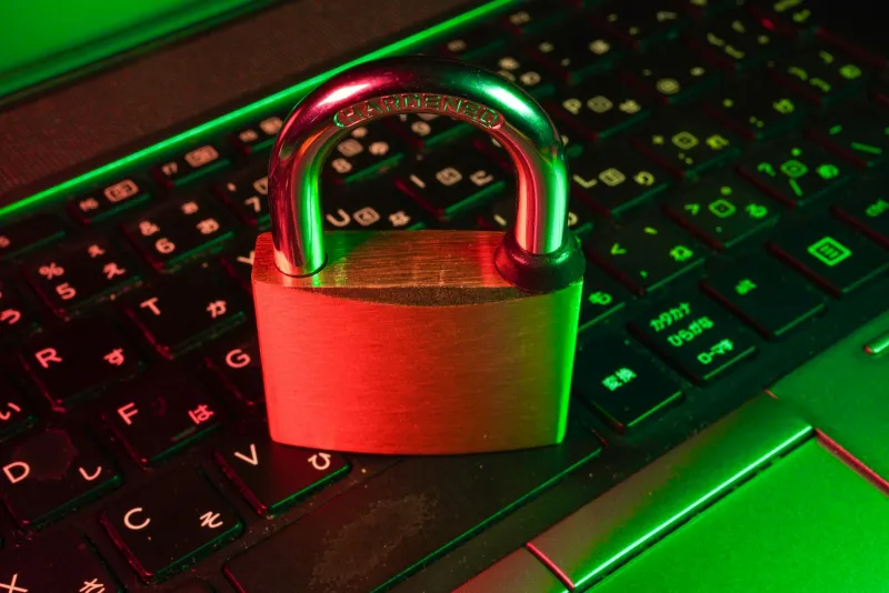A padlock resting on a laptop keyboard lit in red and green